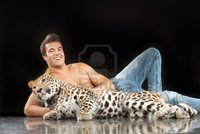 black naked man zigf young man naked torso sits near spotty leopard black background photo